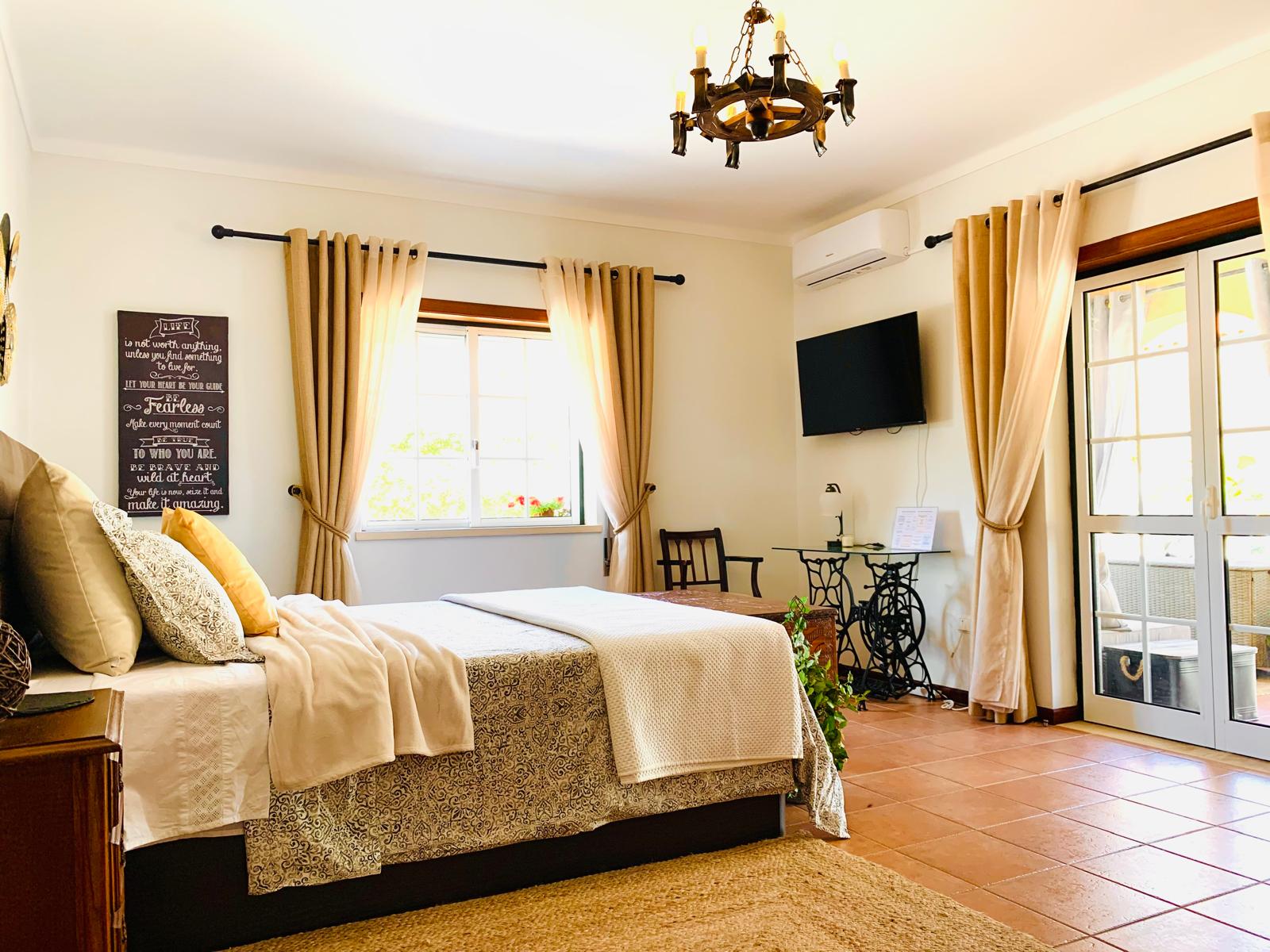 Rose Parlor with queen bed, chandelier, wall-mounted TV and French doors opening to the porch