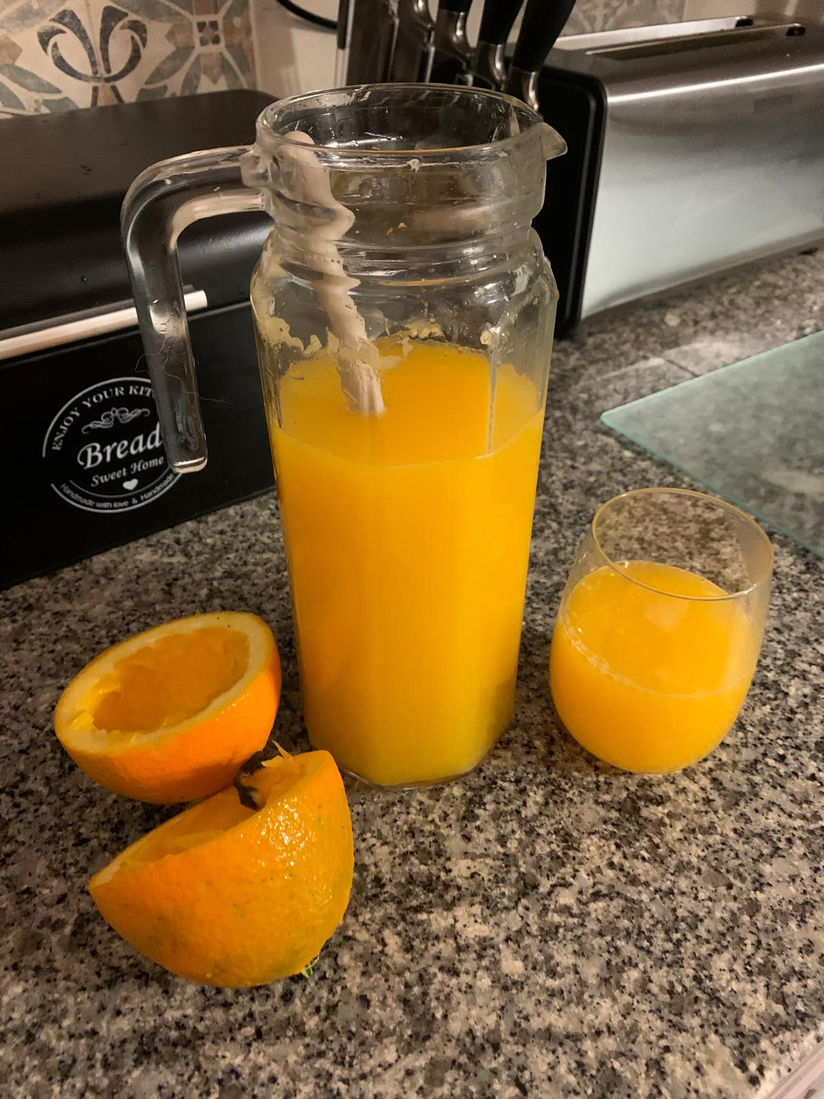 Glass pitcher of fresh-squeezed orange juice with a poured glass beside it
