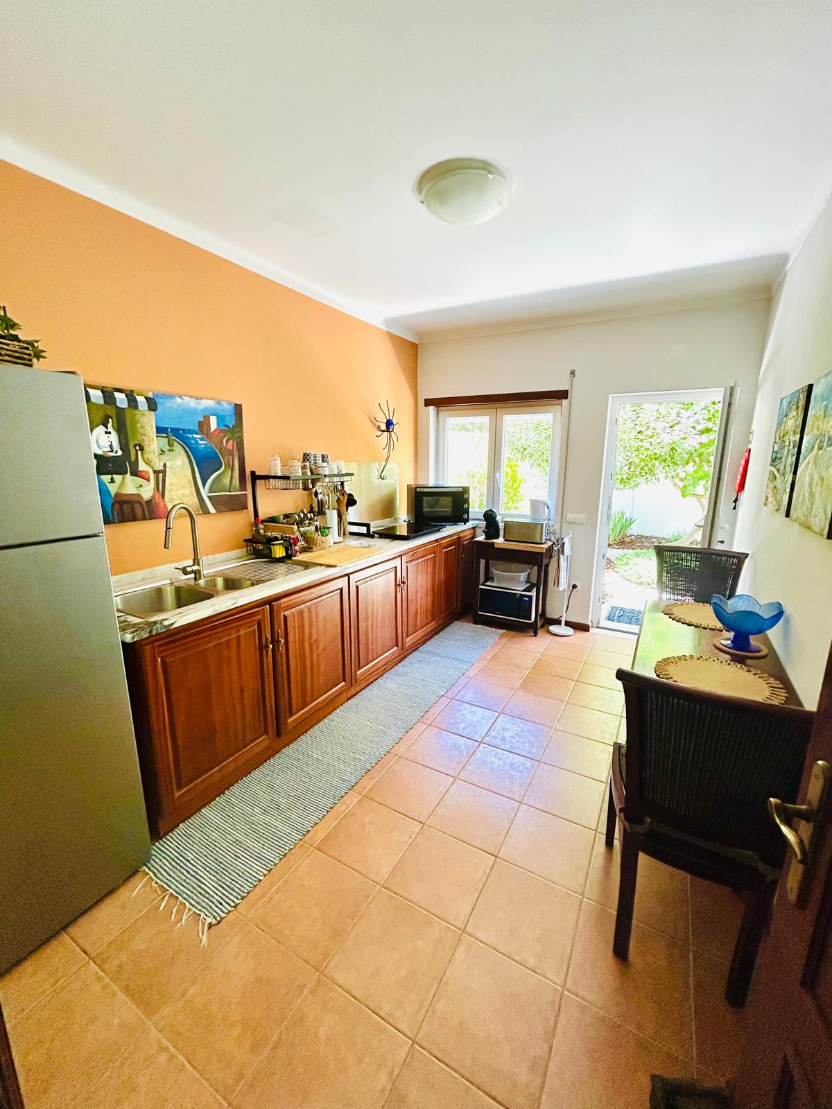 Shared kitchenette with sink, fridge and dining area opening to the garden at Sunrise Villa Alvorada