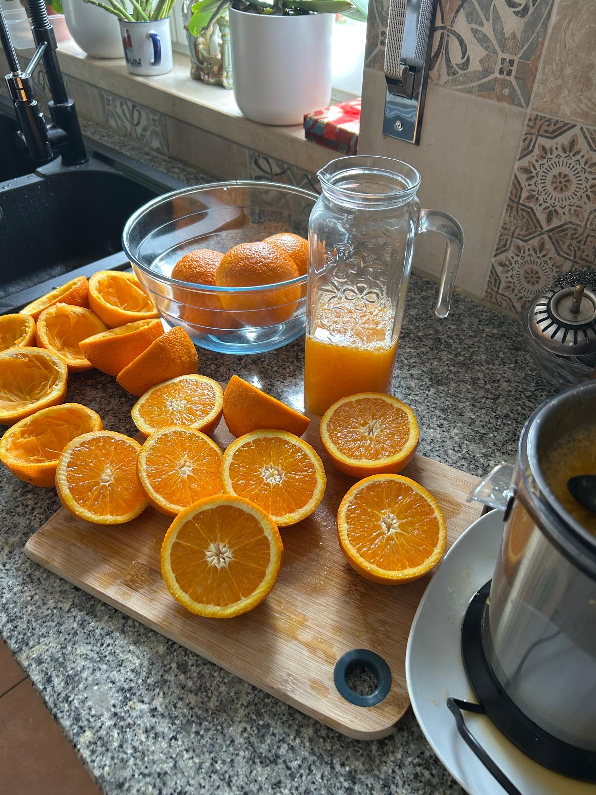 Sliced oranges on a wooden board with a pitcher of fresh-squeezed juice