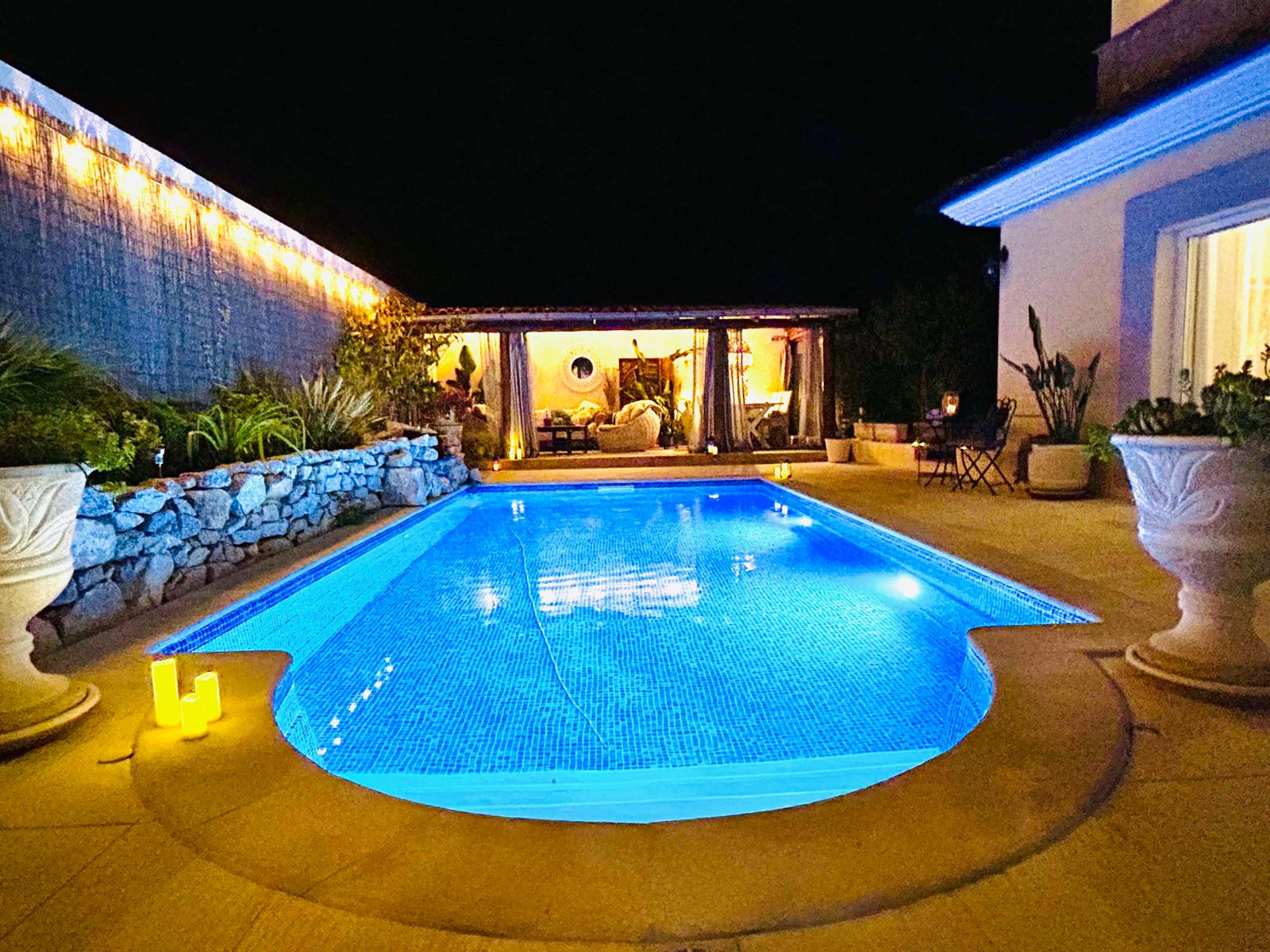 Pool at night with candle lanterns and warm cabana lighting