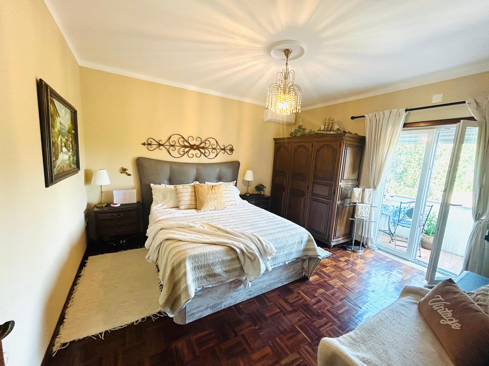The Orchard Lookout — queen bed with chandelier and balcony doors