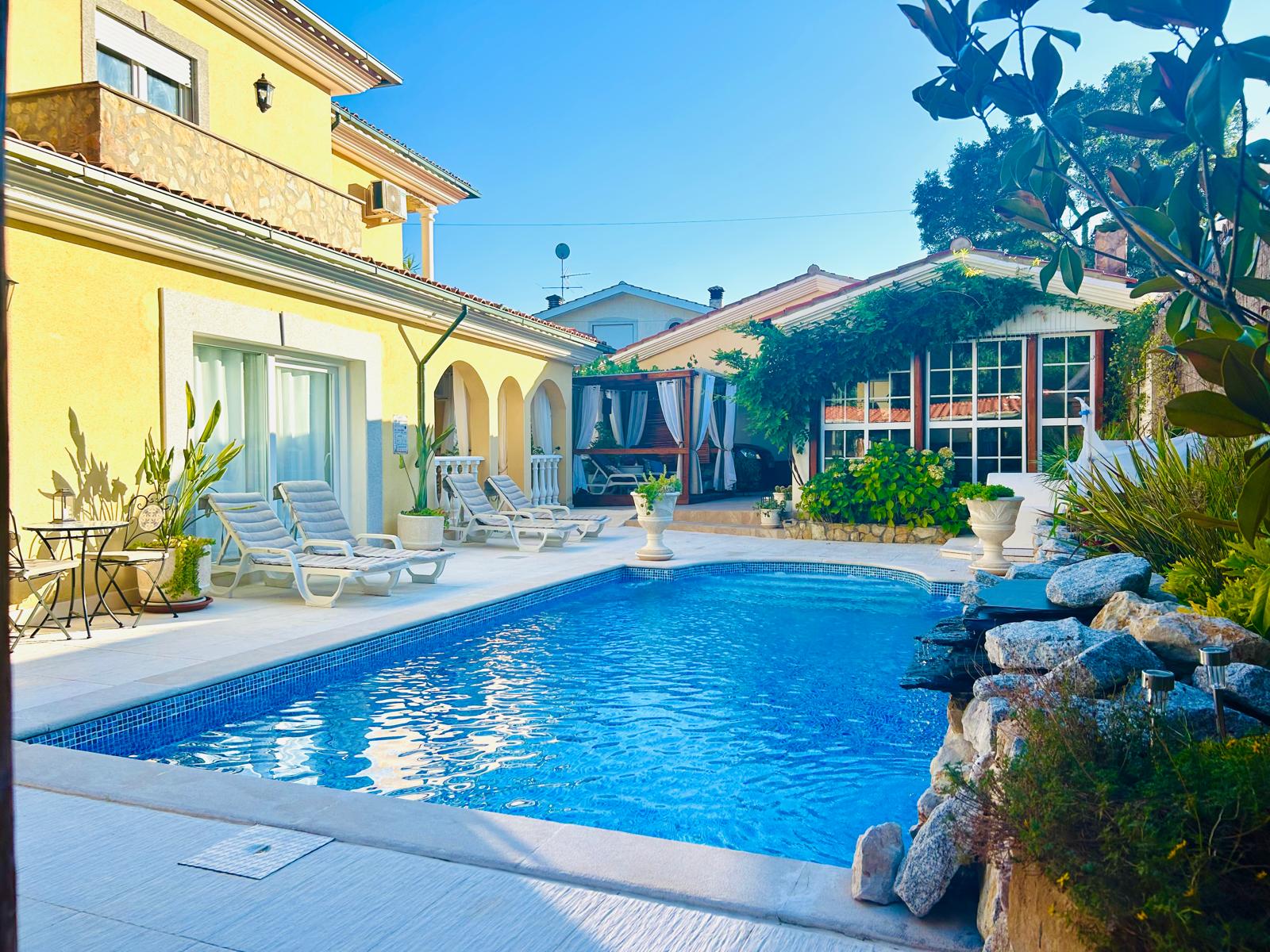 Saltwater pool in bright daylight with loungers and yellow villa