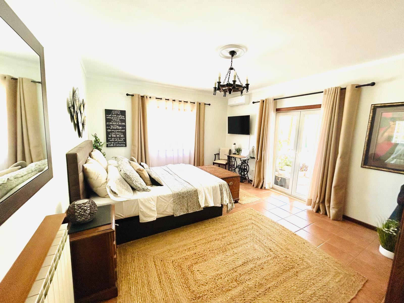 Rose Parlor bedroom with wall-mounted TV, chandelier and French doors opening to the private patio