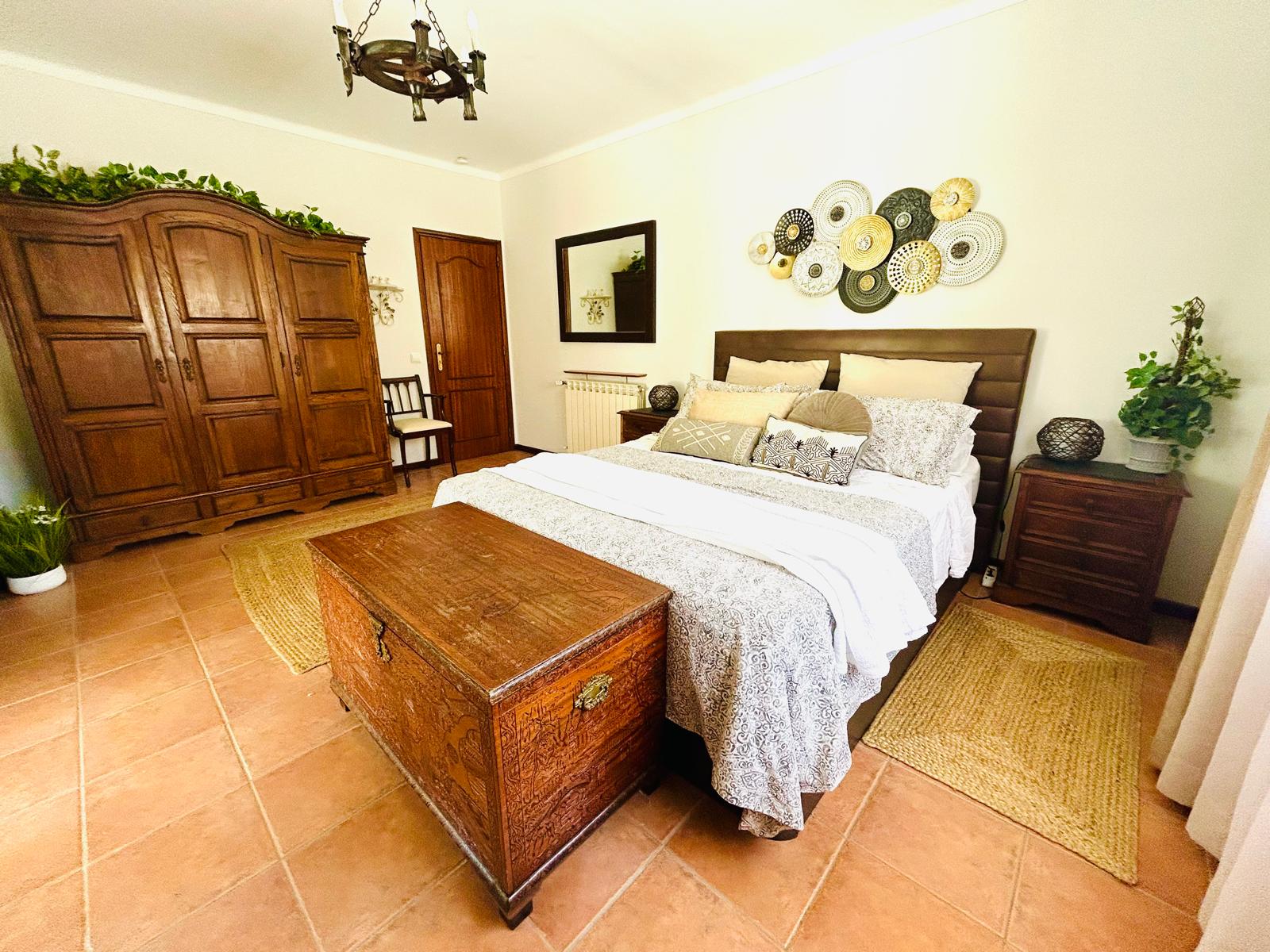 Rose Parlor bedroom with antique oak armoire, iron chandelier and queen bed with carved wooden chest