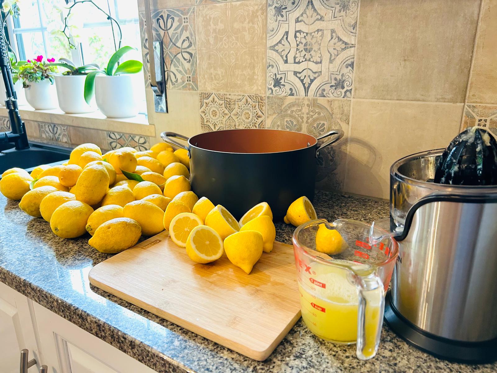Pile of garden lemons on the kitchen counter, halved and ready to juice