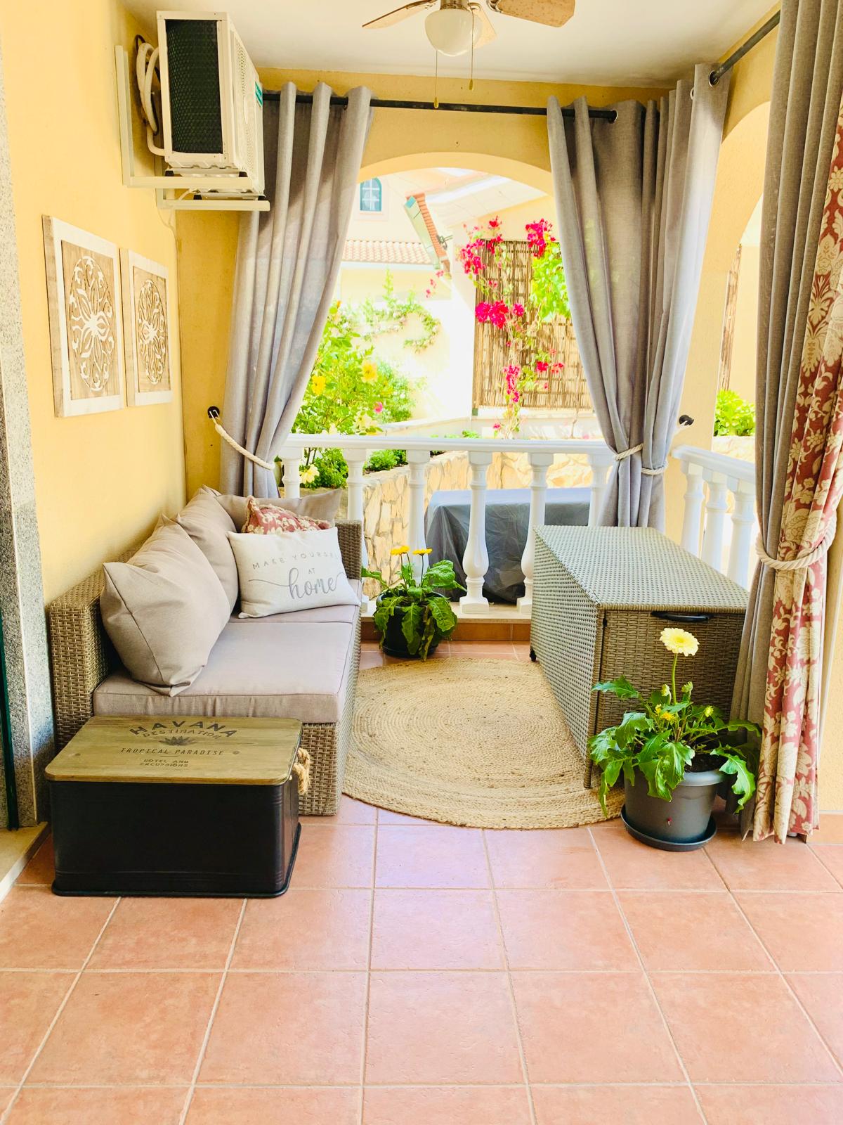 Private porch with wicker sofa, potted plants and bougainvillea beyond the arches