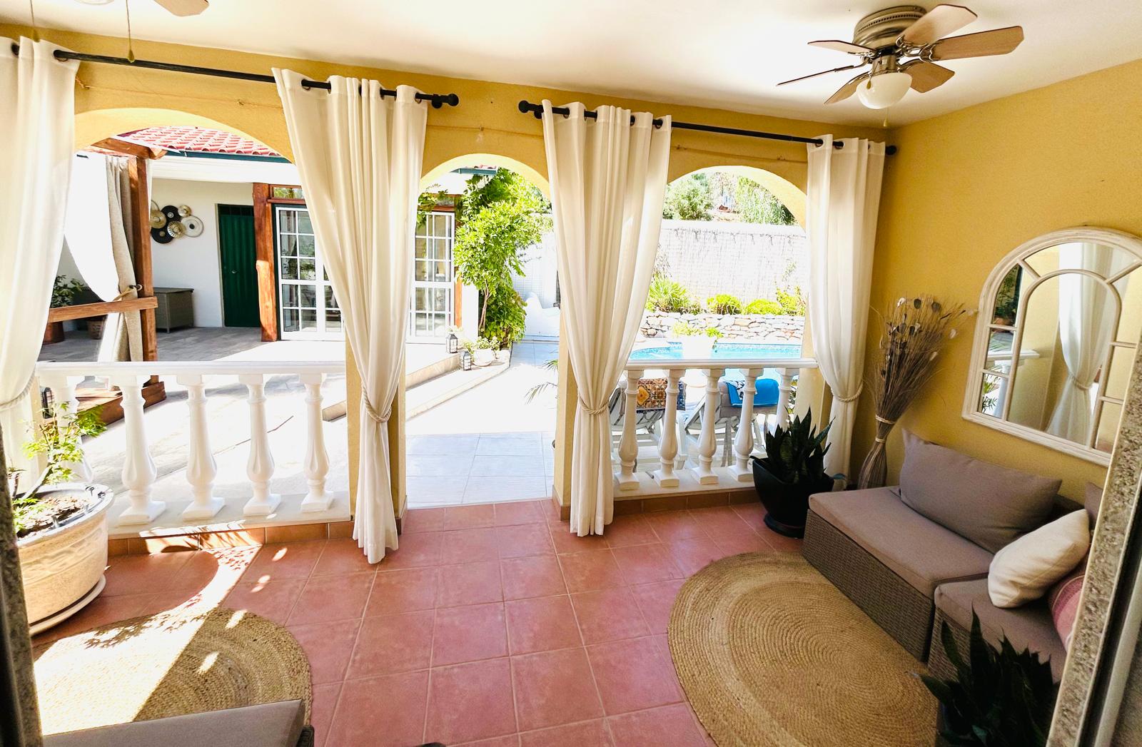 Rose Parlor private porch with arches, flowing white curtains, wicker sofa and view to the pool